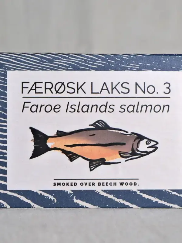 Boks med Færøysk røkt laks fra Fangst, servert med sitronskiver og friske urter på et trebord.